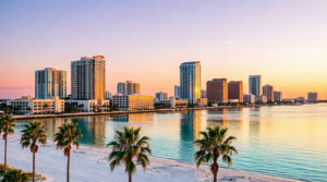 A beautiful sunset over a coastal city with tall buildings, palm trees, and a sandy beach, reflecting colorful light on the calm ocean water—an ideal scene for a private investigator Clearwater to discreetly begin a missing person investigation Florida.