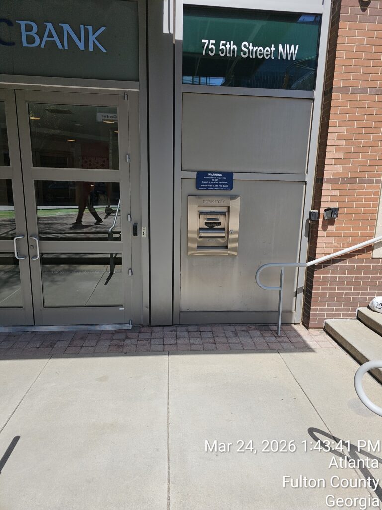 An outdoor ATM is installed next to a glass entrance door of a bank at 75 5th Street NW. The sidewalk is in front, and the date and location info is overlaid at the bottom right of the image.